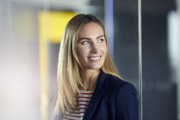 Porträt einer lächelnden Geschäftsfrau im Büro mit Blick zur Seite - RBF07472