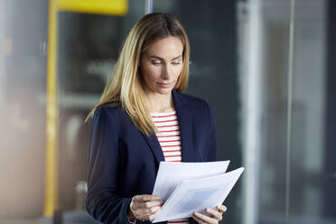 Portait of businesswoman reviewing papers in office - RBF07478