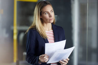 Businesswoman holding papers in office - RBF07479