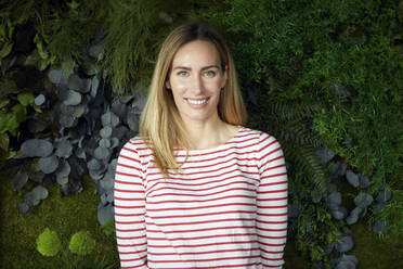 Portrait of smiling woman in front of a green wall - RBF07485