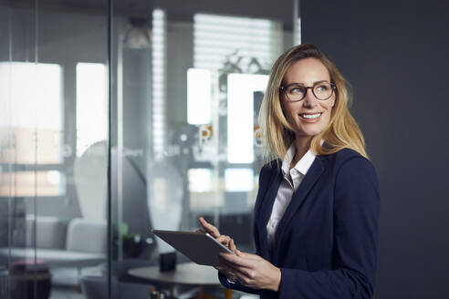 Lächelnde Geschäftsfrau mit Tablet im Büro - RBF07518