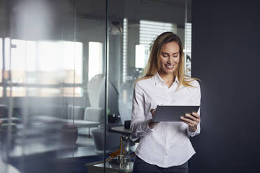 Lächelnde Geschäftsfrau mit Tablet im Büro - RBF07528