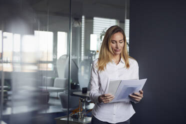 Portait of businesswoman reviewing papers in office - RBF07529