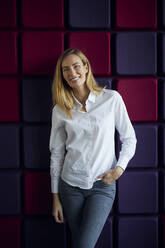 Portrait of smiling woman at a purple wall - RBF07540