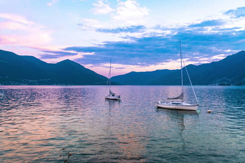 Lake Locarno with sailing boats and mountains in the background sunset - CAVF78706