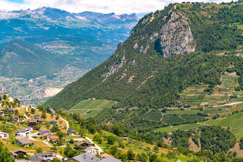 Blick auf ein Dorf in den Alpen im Sommer mit grünen Bergen - CAVF78719