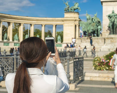 Asiatischer Tourist fotografiert mit Telefon vom Millenniumsdenkmal aus - CAVF78739