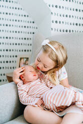 Closeup portrait of two sisters sitting together in a rocking chair - CAVF78857