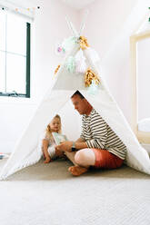 Portrait of a father and daughter reading together in a play tipi - CAVF78863