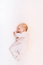 View from above of a newborn baby girl in striped pajamas - CAVF78864