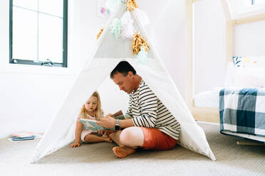 Closeup portrait of a dad and child reading together in a child's room - CAVF78866