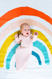 View from above of a newborn baby lying on a rainbow painted blanket - CAVF78878