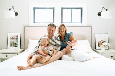 A family of four sitting together in a modern bedroom - CAVF78887