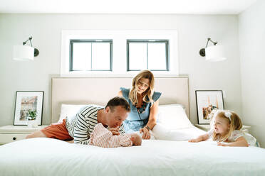 A new family of four playing together in a modern bedroom - CAVF78892