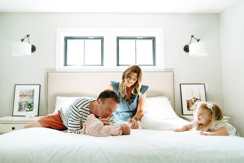 Eine neue vierköpfige Familie spielt zusammen in einem modernen Schlafzimmer - CAVF78892