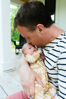 A new dad kissing his newborn baby girl on the forehead - CAVF78929