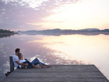 Romantisches Paar auf dem Steg am See sitzend - PNEF02568