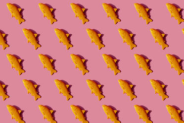 Pattern of yellow plastic fish against pink background - GEMF03526