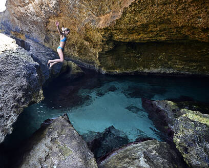 Frau springt in einer Grotte ins klare Wasser - ECPF00868