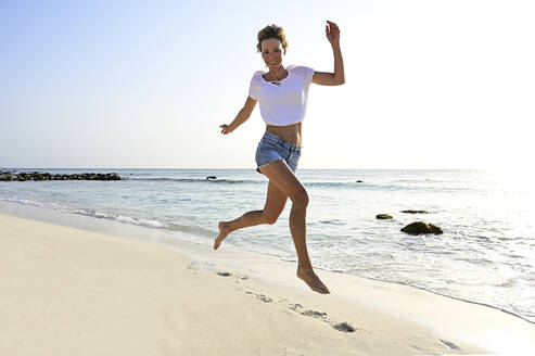 Schöne Frau läuft und springt vor Freude am Strand - ECPF00872