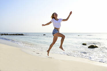 Schöne Frau läuft und springt vor Freude am Strand - ECPF00873
