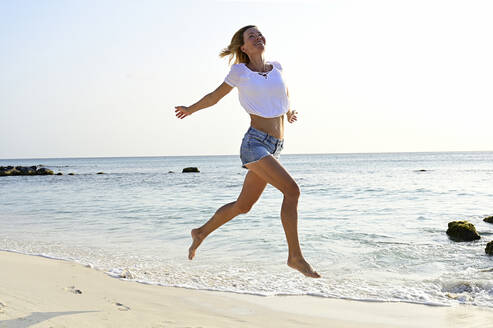 Schöne Frau läuft und springt vor Freude am Strand - ECPF00874