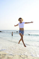 Schöne Frau läuft und springt vor Freude am Strand - ECPF00875