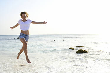 Beautiful woman running and jumping for joy on the beach - ECPF00876