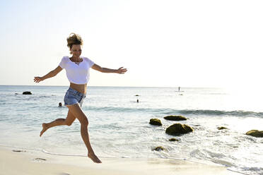 Beautiful woman running and jumping for joy on the beach - ECPF00877