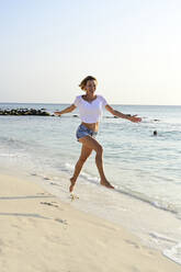 Beautiful woman running and jumping for joy on the beach - ECPF00878