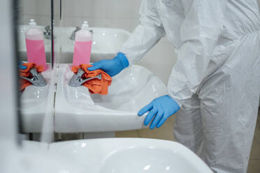 Reinigungspersonal bei der Desinfektion eines Krankenhauses gegen Infektionskrankheiten, in Schutzkleidung, Nahaufnahme - CJMF00295