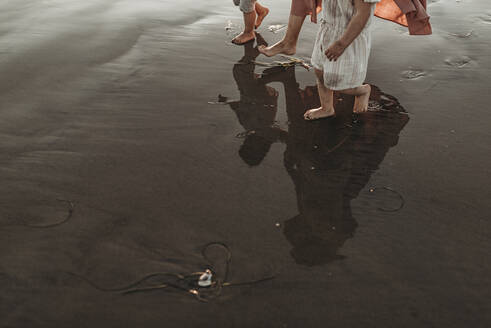 Spiegelung im Meerwasser von Mutter mit zwei Töchtern am Strand - CAVF78947