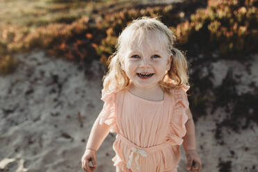 Portrait of young toddler girl with pigtails smiling on beach - CAVF78953