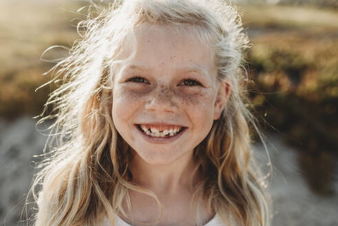 Close up Portrait of young school age girl with freckles smiling - CAVF78954