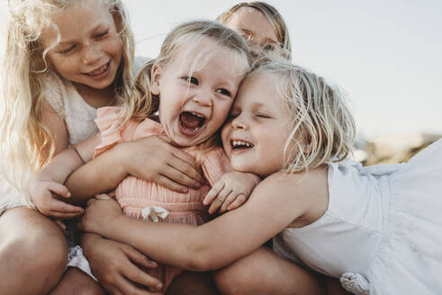 Nahaufnahme eines lachenden Kleinkindes, umgeben von jungen Schwestern - CAVF78955