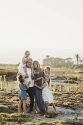 Lifestyle portrait of family with young girls smiling at beach sunset - CAVF78964