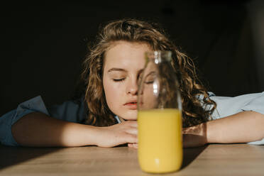 Portrait of blond young woman with closed eyes leaning on tabletop - TCEF00436