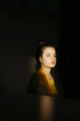 Porträt einer blonden jungen Frau im Sonnenlicht zu Hause - TCEF00459