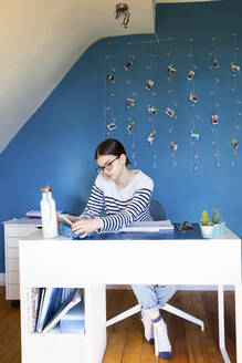 Girl sitting at desk at home doing homework - LVF08760