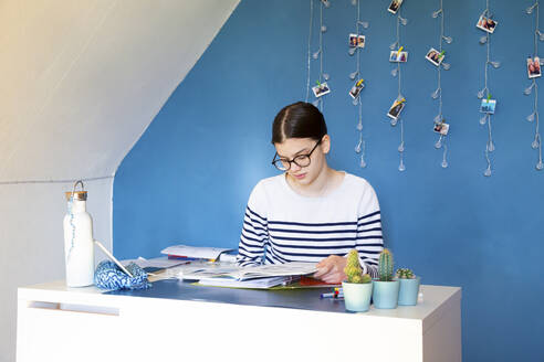 Portrait of girl sitting at desk at home doing homework - LVF08761