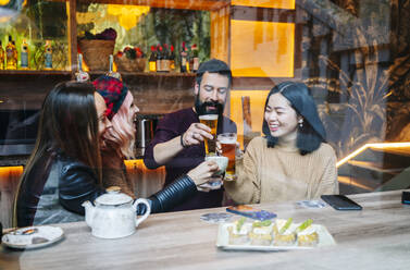 Freunde treffen sich in einer trendigen Bar und stoßen mit Gläsern an - DGOF00679