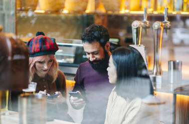 Friends meeting in restaurant, talking, looking at smartphones - DGOF00681