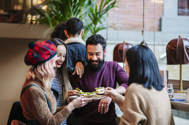 Freunde treffen sich in einer trendigen Bar und teilen Vorspeisen - DGOF00684