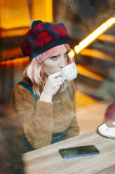 Junge Frau sitzt im Restaurant und trinkt Kaffee - DGOF00689