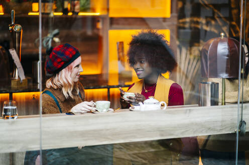 Zwei Freundinnen treffen sich in einem Café und trinken Tee - DGOF00691