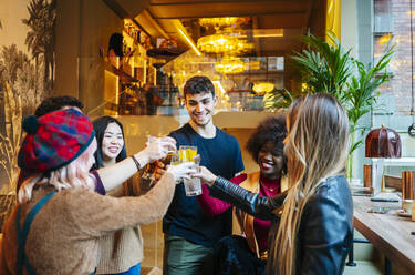 Freunde treffen sich in einer trendigen Bar und stoßen mit Gläsern an - DGOF00699