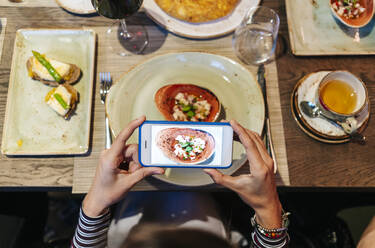 Frau im Restaurant, die mit ihrem Smartphone Essen fotografiert - DGOF00728