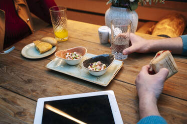 Zwei Menschen sitzen im Restaurant, essen und trinken, mit digitalem Tablet auf dem Tisch - DGOF00768