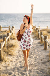 Junge Frau mit erhobenem Arm bei einem abendlichen Spaziergang am Strand - MPPF00754