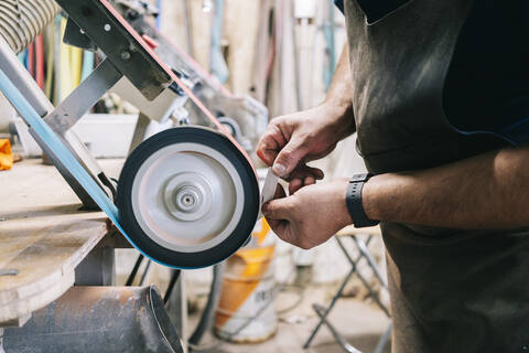 Craftsman making knives in his workshop sharpening the blade stock photo